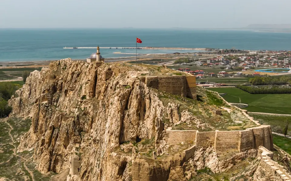 Aerial view of Van Castle on its steep rocky ridge overlooking the blue waters of Lake Van and the city of Van, eastern Turkey.