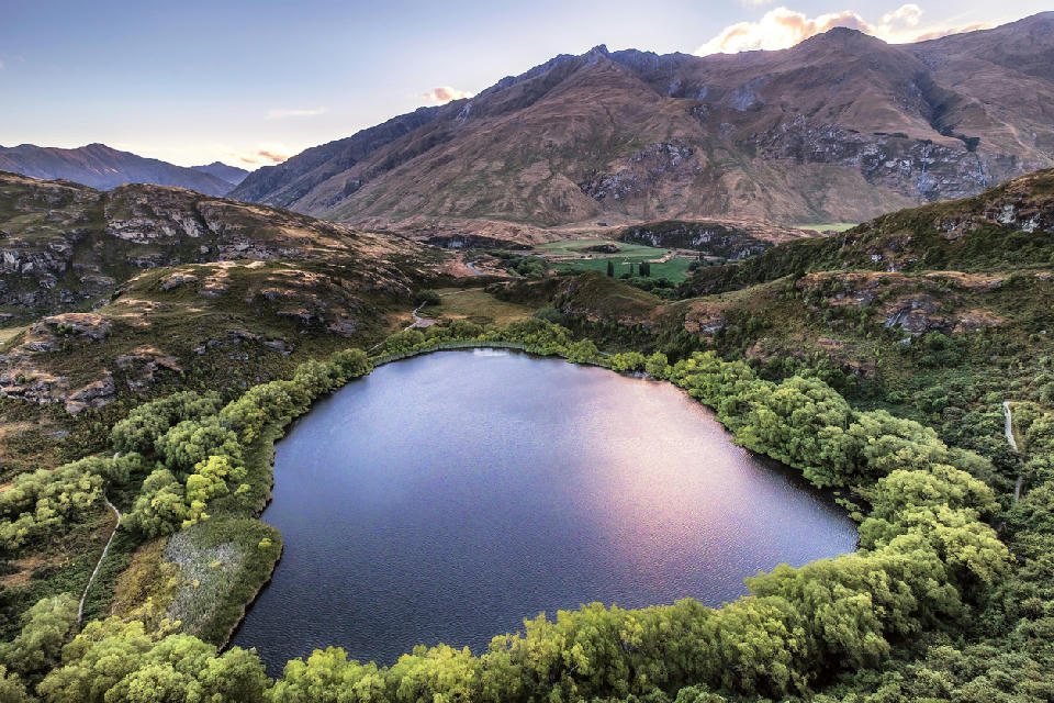 Aerial view of Diamond Lake surrounded by forest and hills near Wānaka, Otago, South Island, New Zealand.