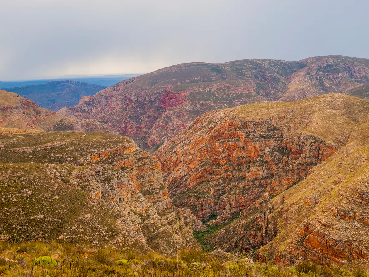 Canyon landscape of the Red Stone Hills near Oudtshoorn in the Little Karoo with layered red rock cliffs and rugged semi-arid terrain in South Africa