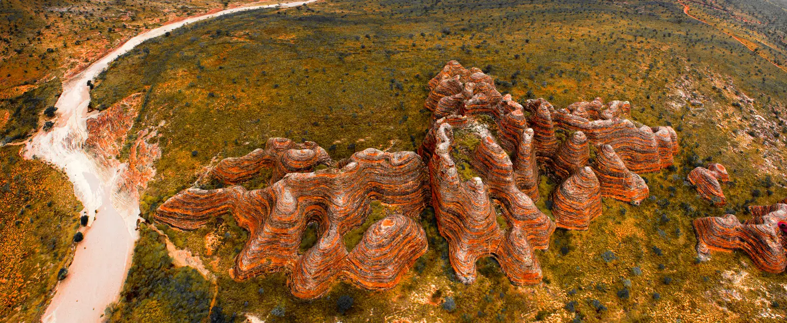 Aerial view reveals the extraordinary striped sandstone formations and narrow valleys of the Bungle Bungle Range surrounded by remote Kimberley wilderness.