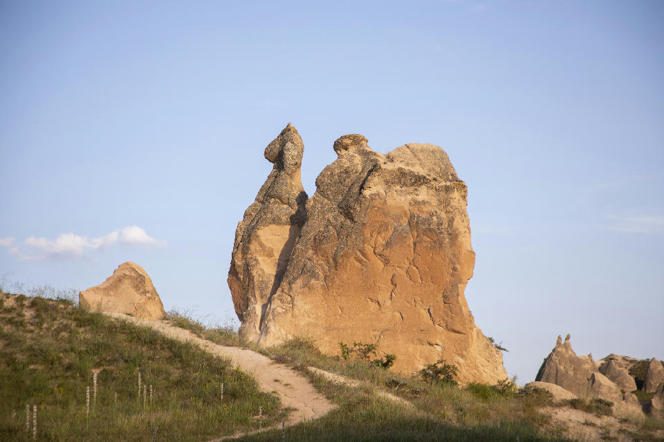 The naturally sculpted Camel Rock formation rising above the volcanic landscape of Devrent Valley (Imagination Valley) in Cappadocia, Turkey, illuminated by warm evening light.