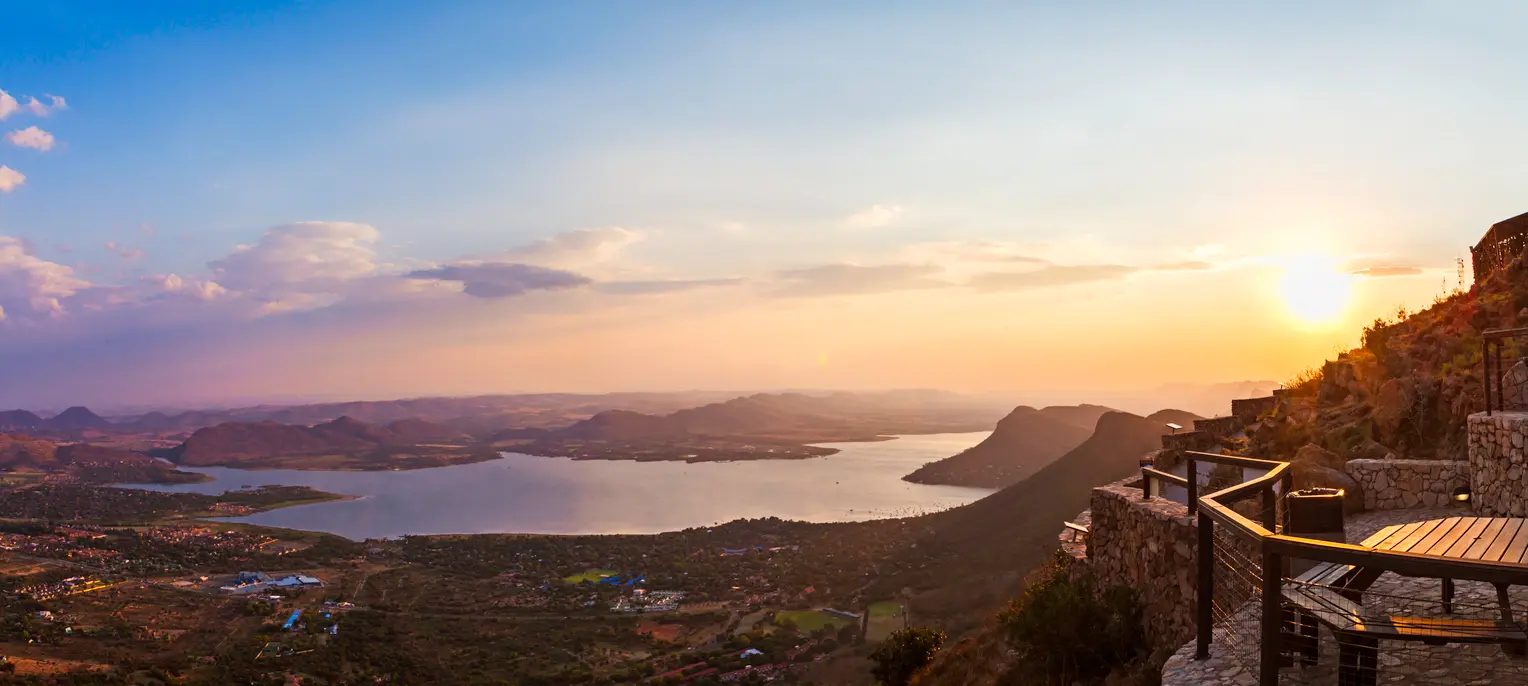 Golden sunset over Hartbeespoort Dam viewed from the summit of the Hartbeespoort Aerial Cableway, with mountain ridges, lakeshore settlements and viewing terraces in the foreground.