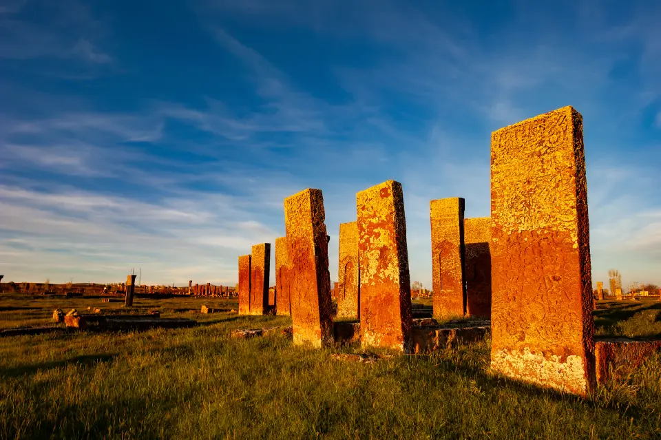 Tall carved medieval gravestones at the historic Ahlat cemetery illuminated by warm evening light in eastern Turkey.