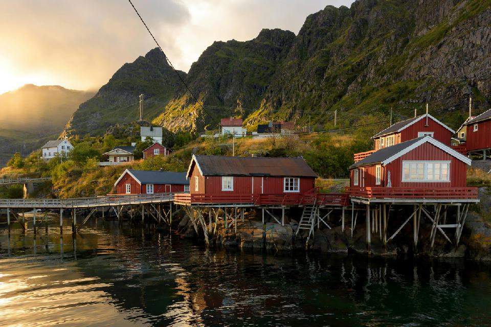 Red rorbuer cabins on stilts in Å on Moskenesøya at sunset, Lofoten Islands, Norway.