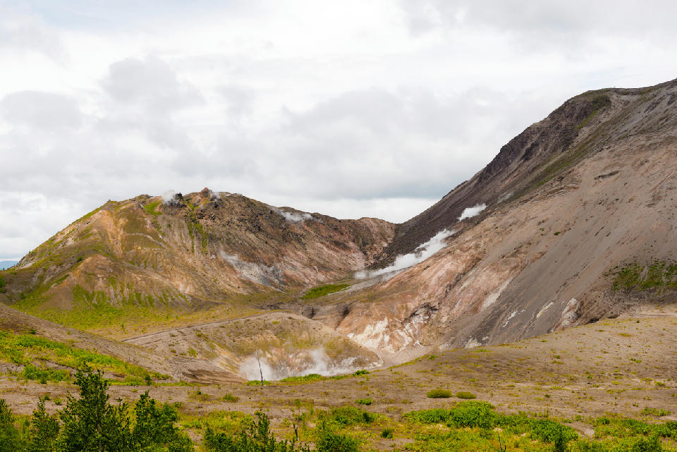 Steaming crater slopes of Mount Usu showing active volcanic vents in Hokkaido, Japan.