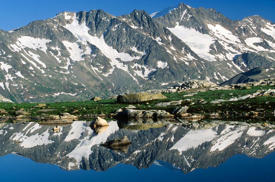 Alpine lake reflecting snow-covered peaks in Vanoise National Park, French Alps