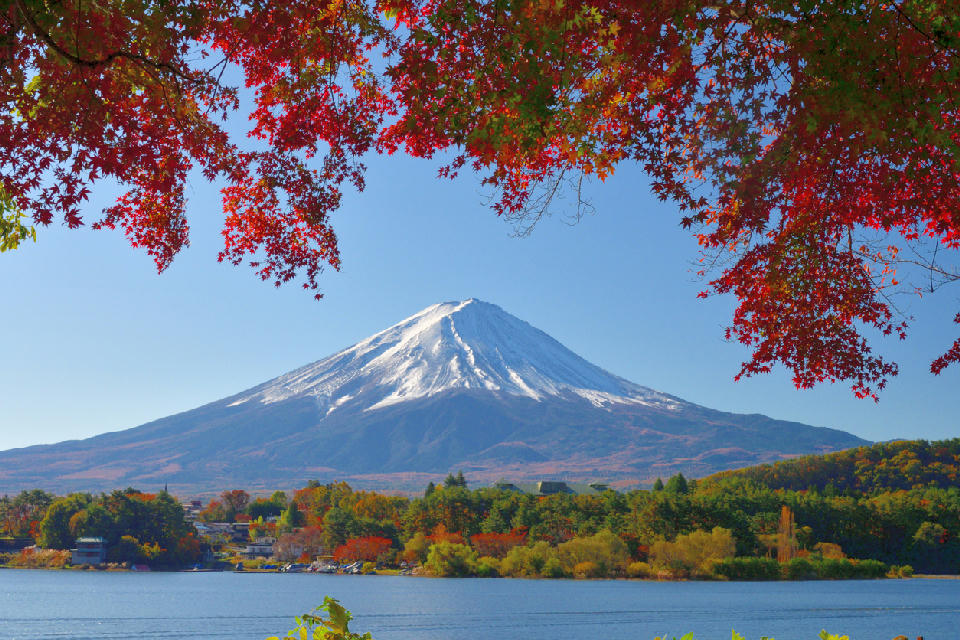 Mount Fuji framed by red autumn leaves above Lake Kawaguchi in Yamanashi, Japan.