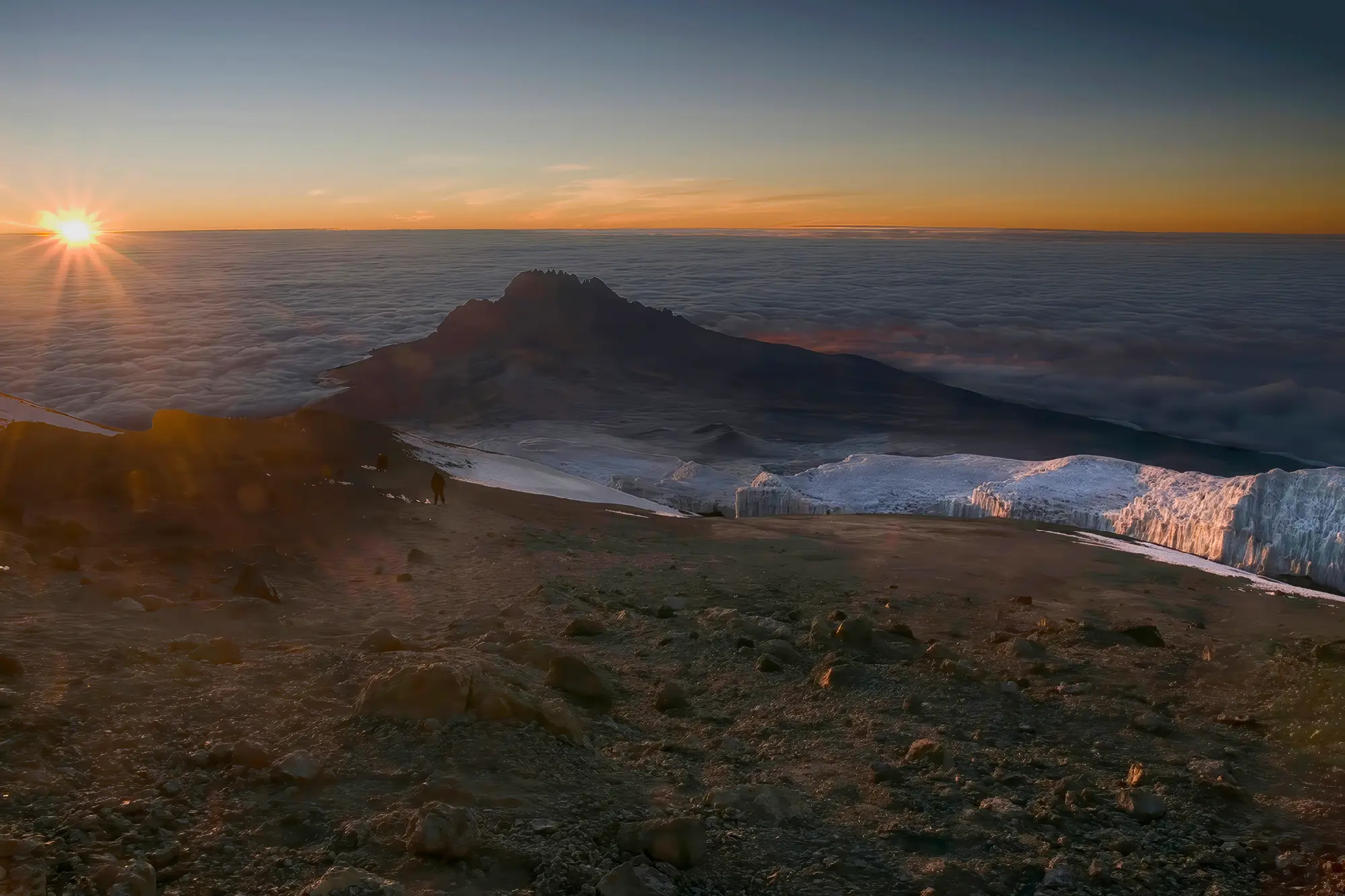 Sunrise near Uhuru Peak on Mount Kilimanjaro with glaciers, Mawenzi Peak and a sea of clouds, Tanzania.