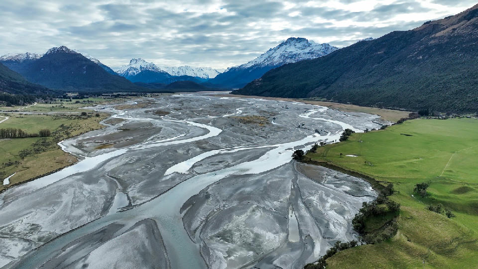 Aerial view of the braided Dart River flowing through a wide valley toward Lake Wakatipu near Glenorchy, South Island, New Zealand.