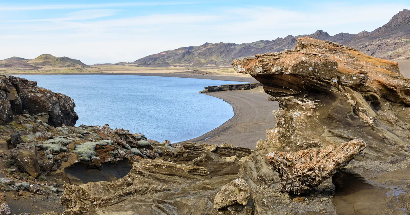 Rock formations overlooking Kleifarvatn lake with volcanic mountains in the background on the Reykjanes Peninsula, Iceland.