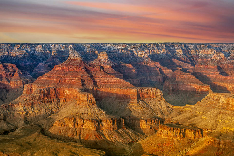 Grand Canyon South Rim at sunset showing layered mesas and buttes with warm light across the canyon landscape