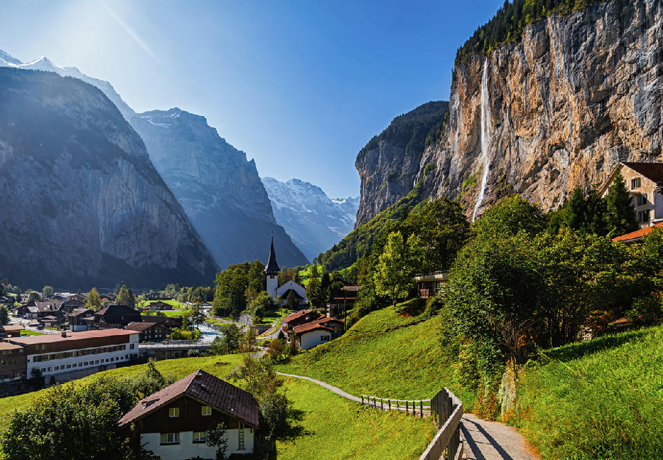 Staubbach Falls flowing down a high cliff above Lauterbrunnen village with alpine valley and mountains in Switzerland