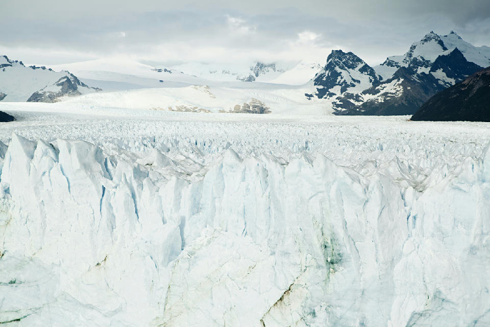Close view of Upsala Glacier ice wall with jagged crevasses and Andean peaks in the background near El Calafate, Patagonia, Argentina.