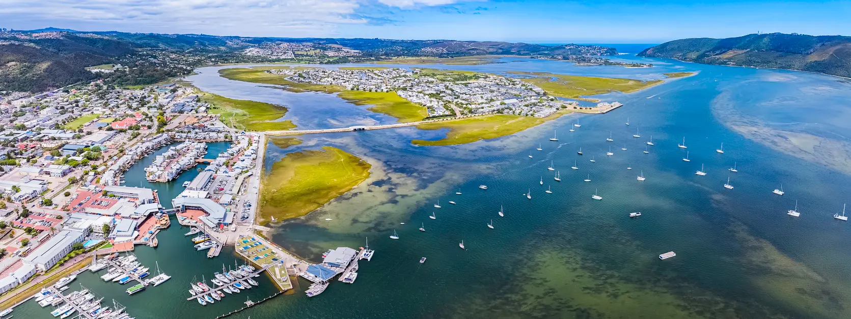 Aerial view of the Knysna Lagoon, showing tidal channels, islands, marinas and waterfront neighbourhoods within South Africa's largest estuary system on the Garden Route.
