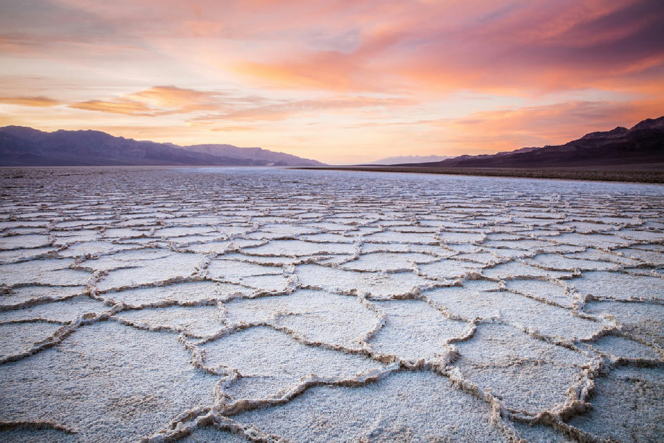 Badwater Basin salt flats at sunset in Death Valley National Park California with polygon salt patterns and distant desert mountains