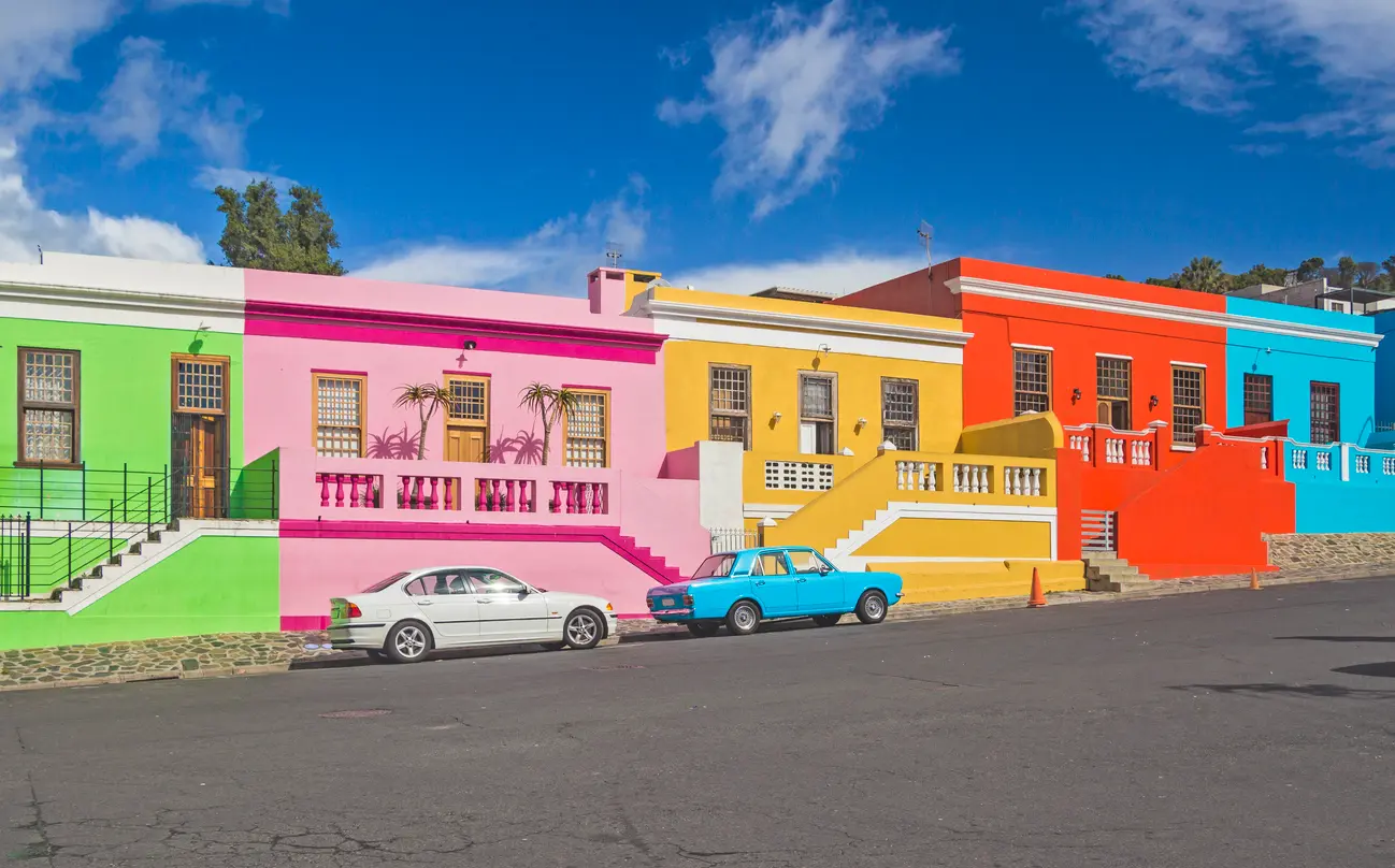 Colorful pastel houses with decorative balconies on a sloping street in Bo-Kaap, Cape Town, South Africa.