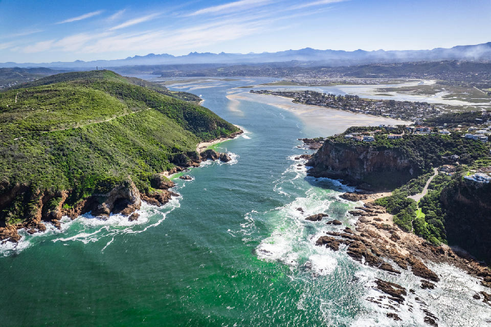 Aerial view of the Knysna Heads and estuary entrance, where steep coastal headlands frame the channel linking the Indian Ocean to the expansive Knysna Lagoon on South Africa's Garden Route.