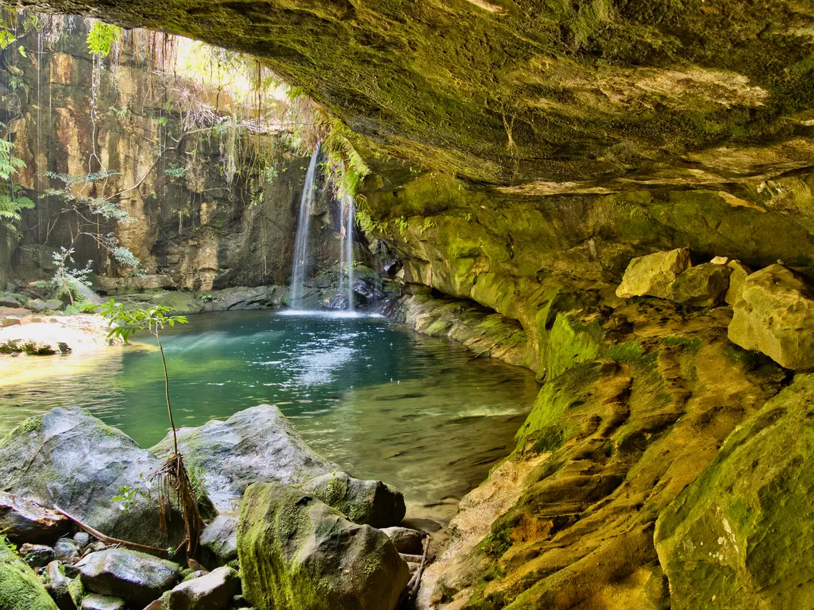 Hidden emerald pool and waterfall beneath a sandstone overhang in Isalo National Park, Madagascar
