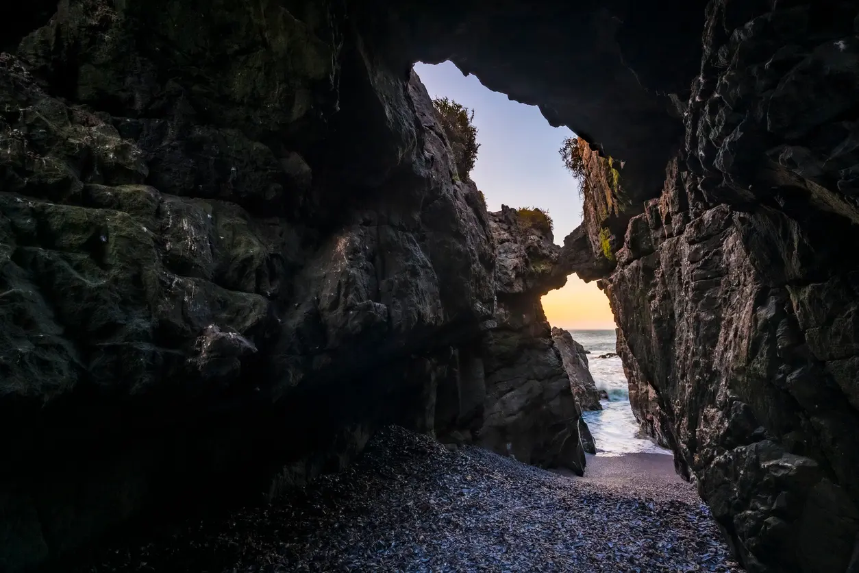 Rock tunnel and natural arch at Duiwenes in Pearl Bay with Atlantic Ocean visible through the opening near Yzerfontein.