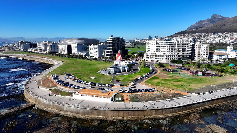 Aerial view of Green Point Lighthouse and the Sea Point Promenade in Cape Town with Table Mountain in the background.