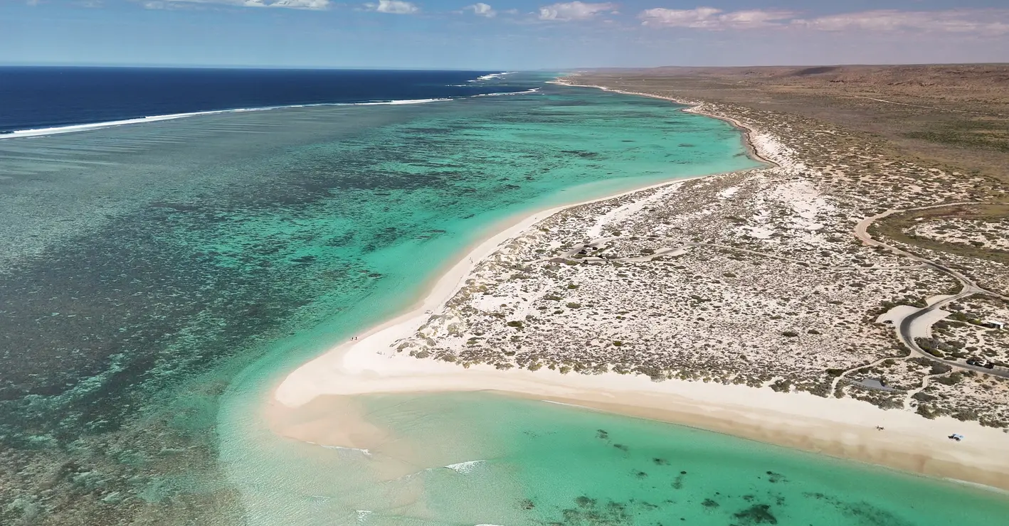 Aerial view of Turquoise Bay with white sand, turquoise lagoon and Ningaloo Reef extending along the coast.