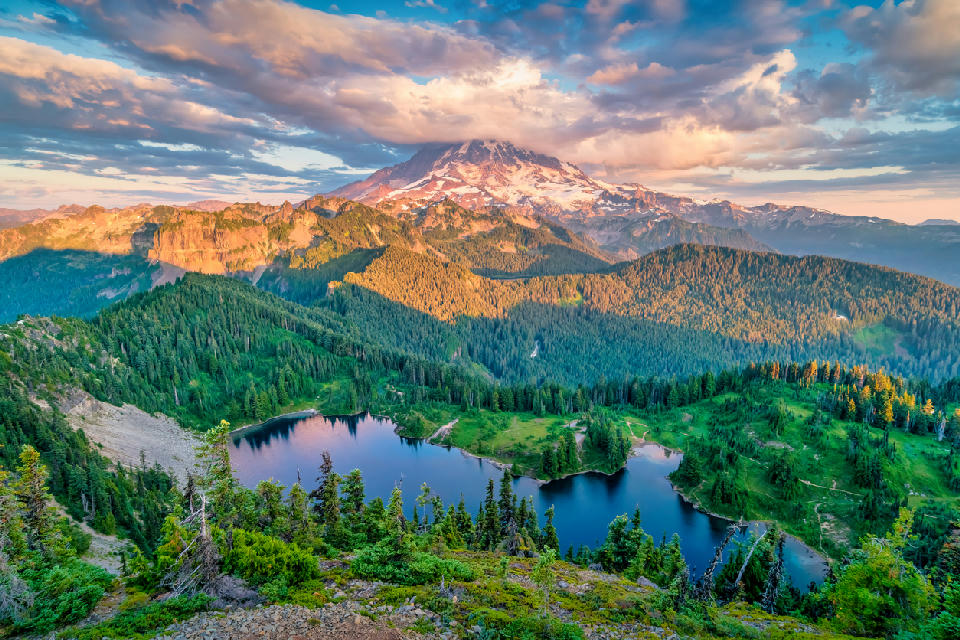 Mount Rainier rising above Eunice Lake with forested ridges and warm sunset light, viewed from Tolmie Peak, Washington State