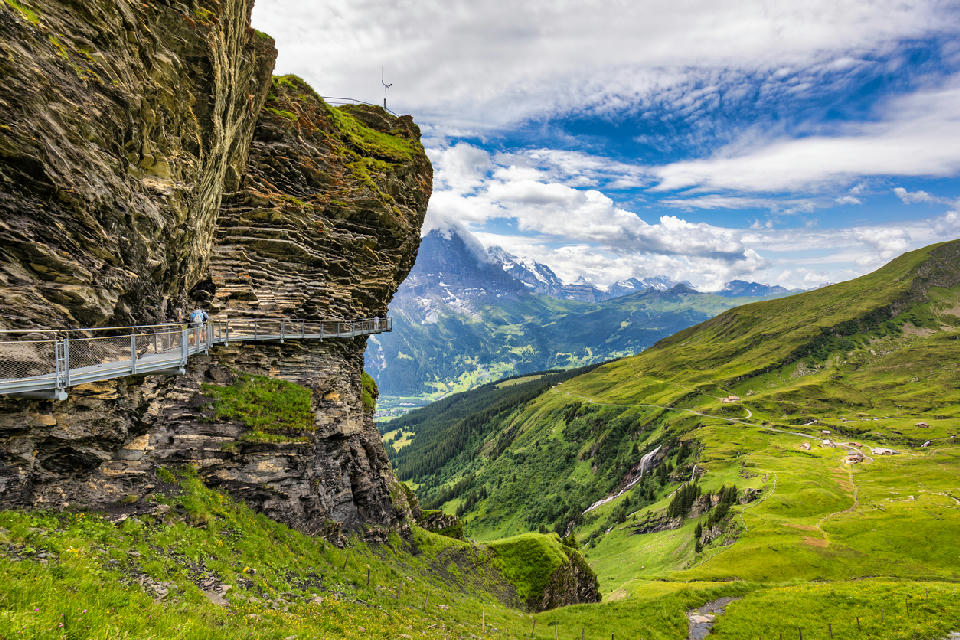Grindelwald First Cliff Walk attached to a rock face overlooking green alpine slopes and the valley below, Bernese Alps, Switzerland.