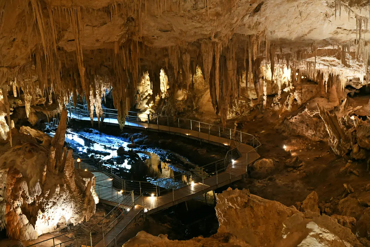 Stalactites and limestone formations surrounding an illuminated walkway inside Mammoth Cave near Margaret River, Western Australia.