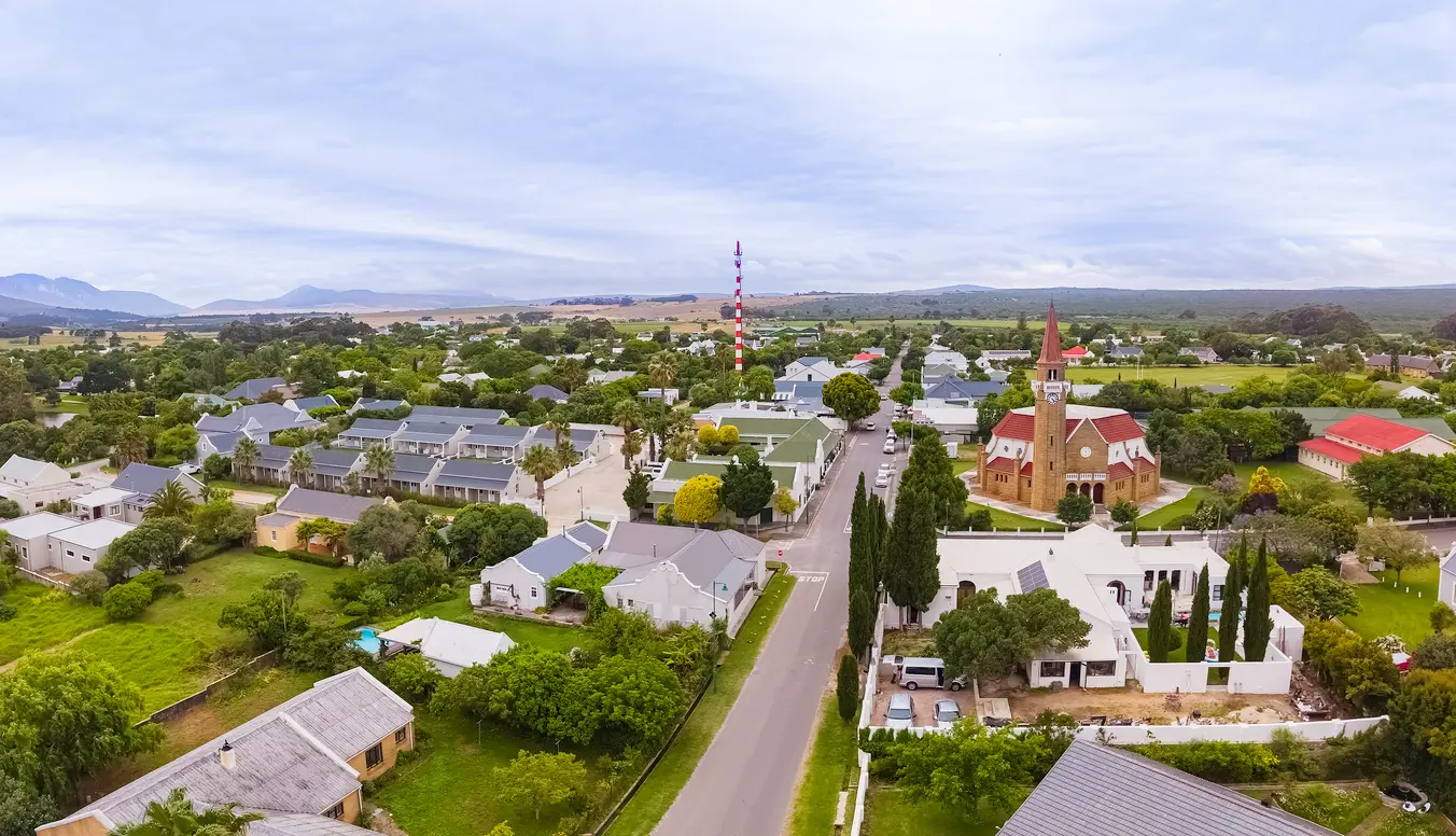 Aerial view of Stanford town with church, tree-lined streets, and surrounding farmland in the Overberg region of the Western Cape, South Africa.