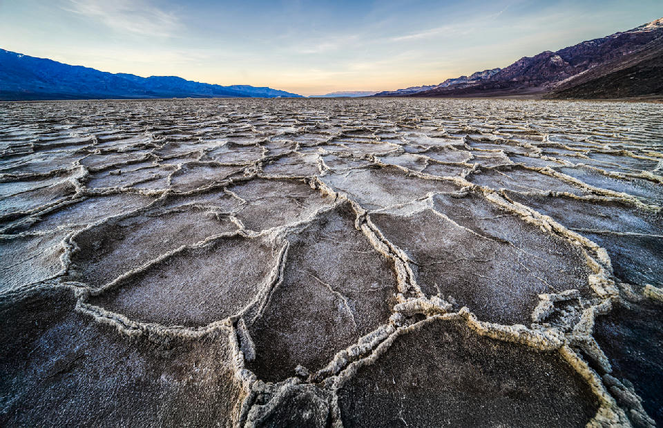 Close-up salt polygon patterns at Badwater Basin in Death Valley with mountains in the background