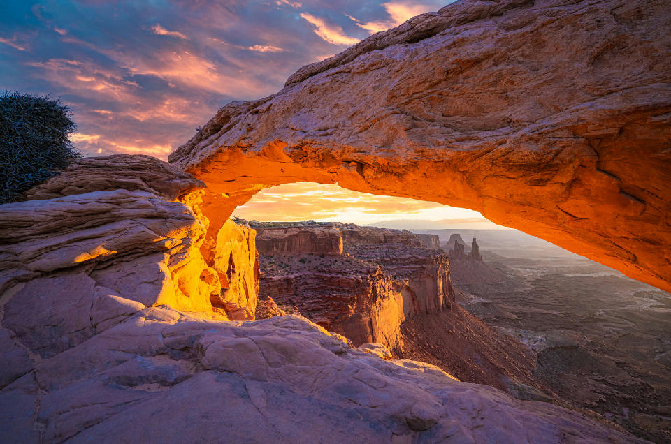 Sunrise glow under Mesa Arch overlooking canyon in Canyonlands National Park Utah