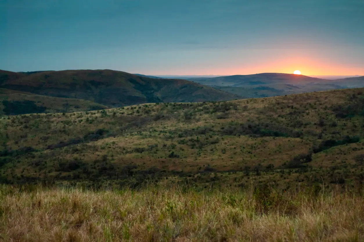 Sunrise across the hills and savanna landscape of Hluhluwe–iMfolozi Park, South Africa.