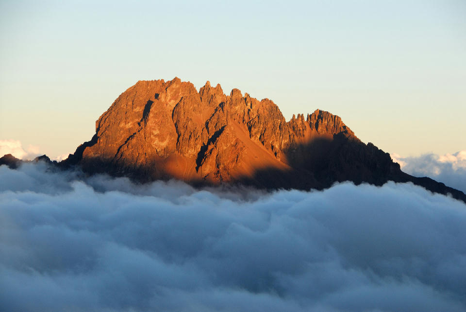 Golden evening light illuminating Mawenzi Peak (5,149 m) above clouds on Mount Kilimanjaro, Tanzania, viewed from approximately 4,700 metres above sea level.