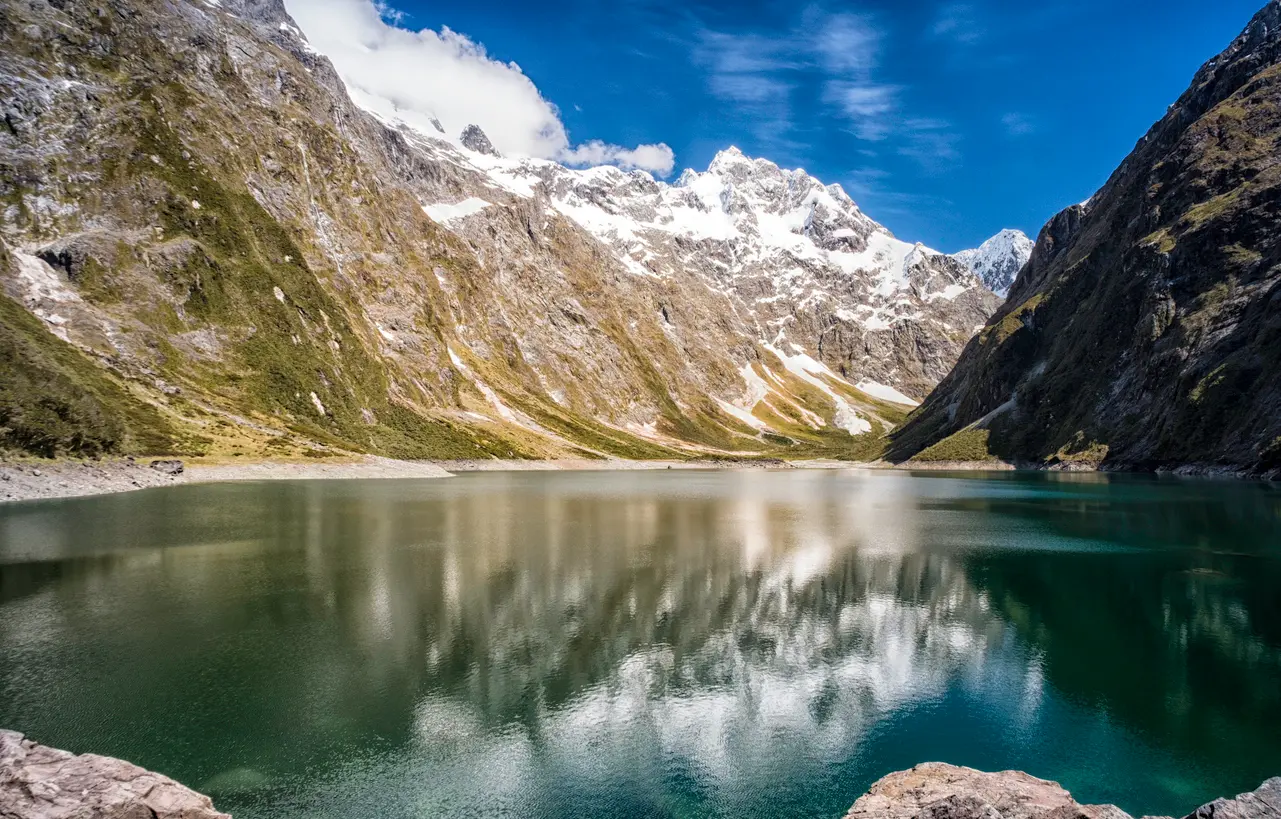 Lake Marian surrounded by steep snow-capped mountains in Fiordland National Park, South Island, New Zealand.