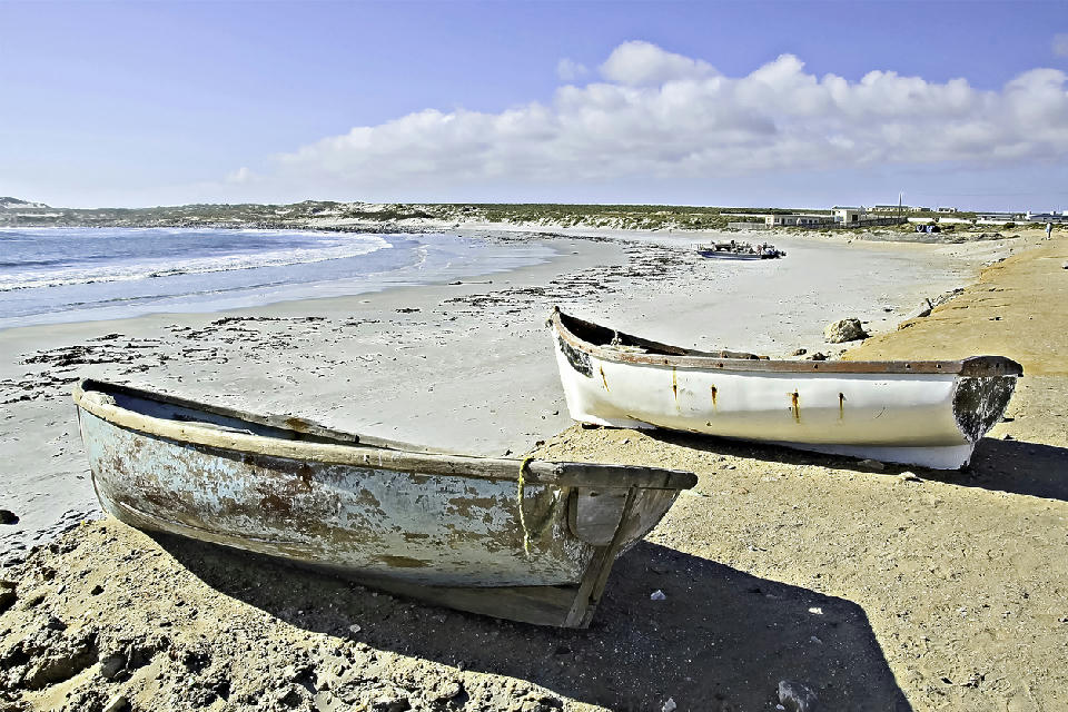 Traditional fishing boats on the sandy shoreline of Hondeklip Bay along the Atlantic coast of Namaqualand, South Africa.