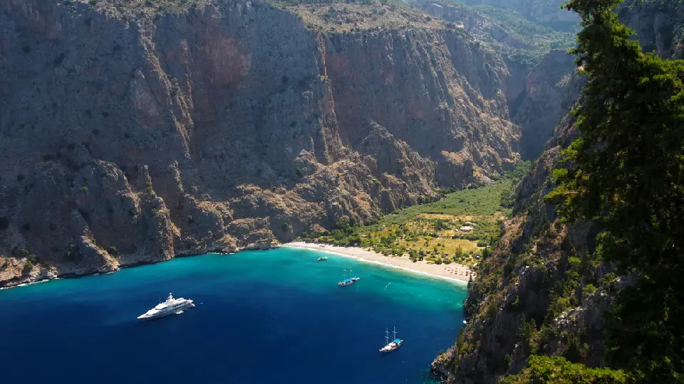 Butterfly Valley's beach and turquoise bay surrounded by towering cliffs near Ölüdeniz, Türkiye.