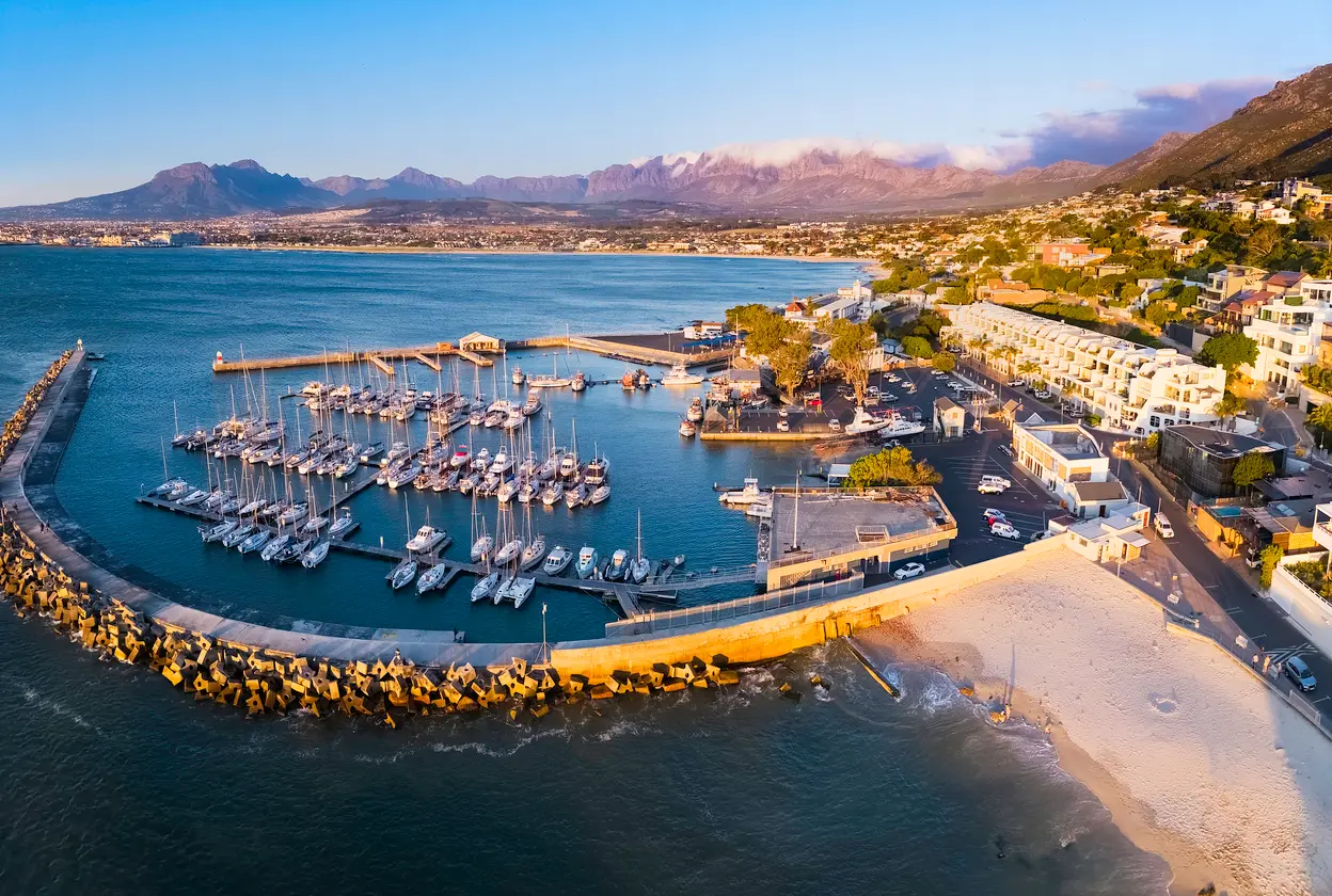 Aerial sunset view of Gordon's Bay Harbour, marina and waterfront with the Hottentots-Holland Mountains and False Bay in the background.
