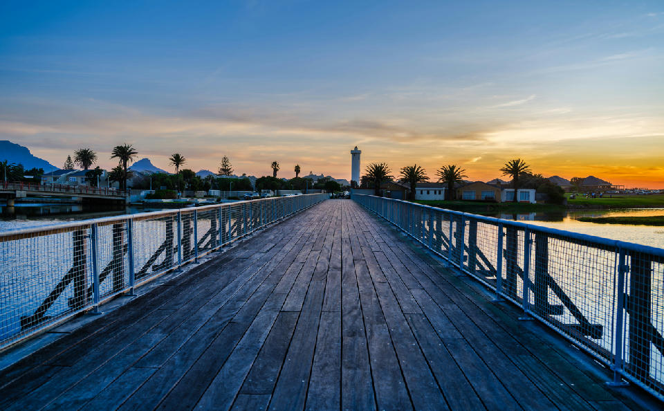Woodbridge Island pedestrian bridge leading to Milnerton Lighthouse at sunset, Milnerton Lagoon, Cape Town, South Africa.