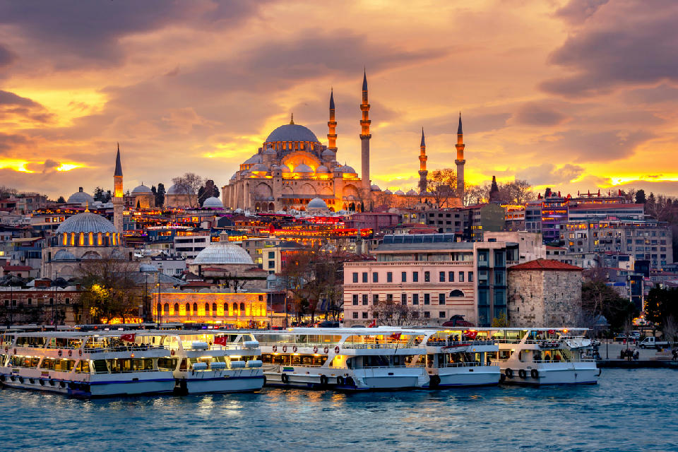Istanbul waterfront and ferries at sunset with the Süleymaniye Mosque rising above the historic peninsula.