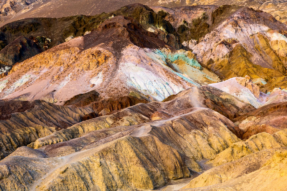 Colorful mineral hills at Artist’s Palette, Death Valley National Park, California, showing pastel green, pink, yellow and purple slopes in desert badlands.