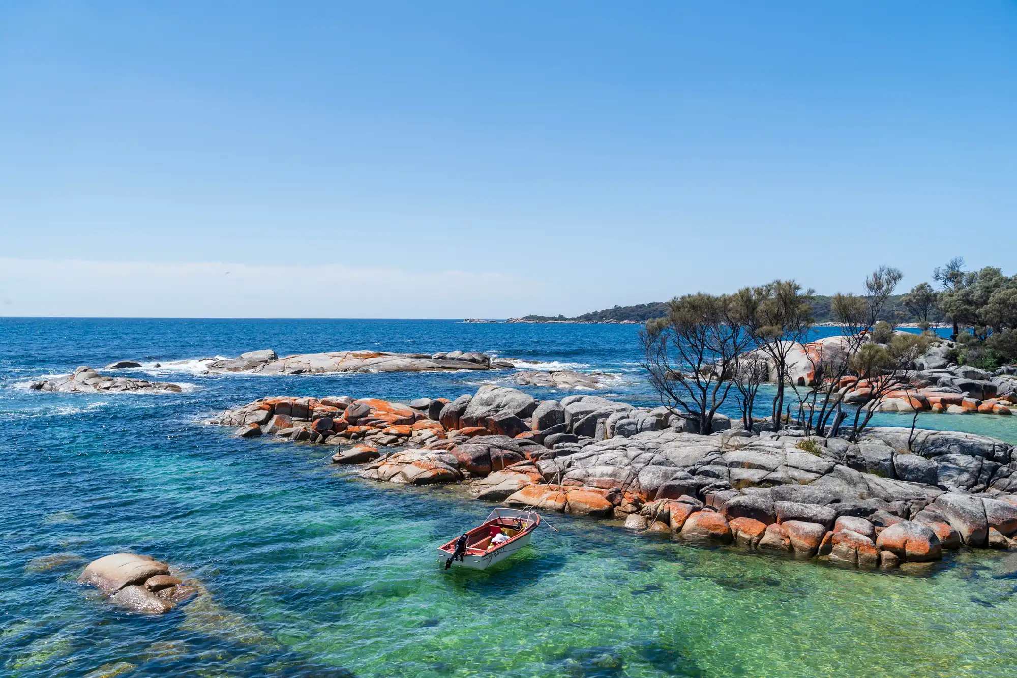 Orange granite rocks and clear turquoise water at Binalong Bay in the Bay of Fires, Tasmania, Australia.