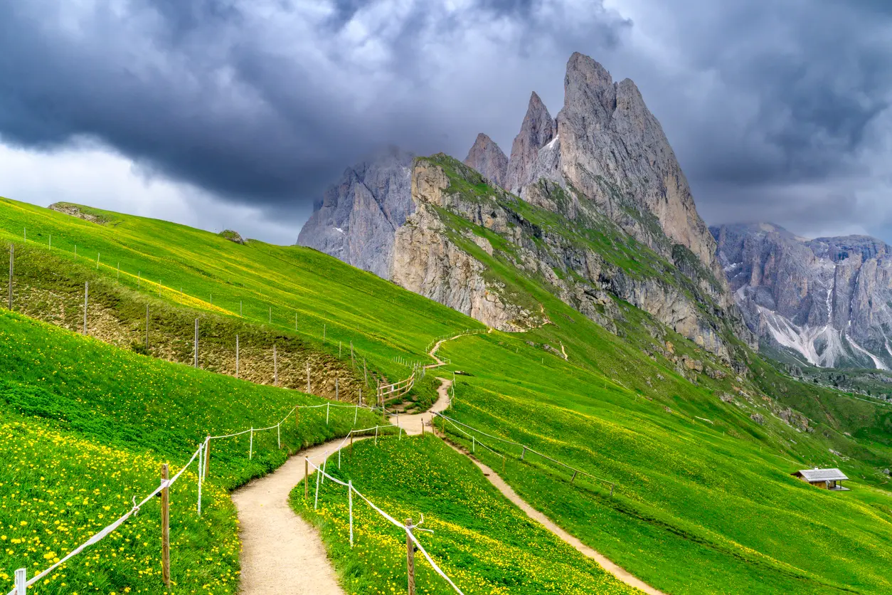 Dramatic cliffs of Seceda under overcast conditions, with views toward the Odle (Geisler) Group, Dolomites, South Tyrol, Italy.