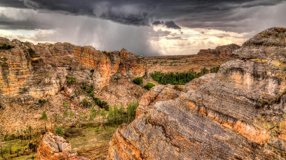 Storm clouds gather above the layered sandstone canyons of Isalo National Park in southwestern Madagascar