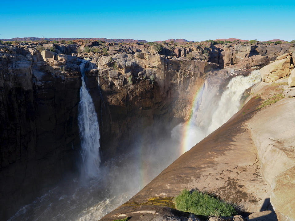 Augrabies Falls cascading into a granite gorge with a rainbow forming in the spray, Northern Cape, South Africa.