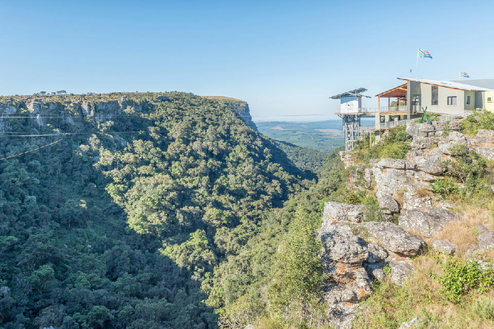 Graskop Gorge Lift visitor centre perched on the edge of a forested gorge, with adventure activities including a zipline and Big Swing visible in Mpumalanga, South Africa.