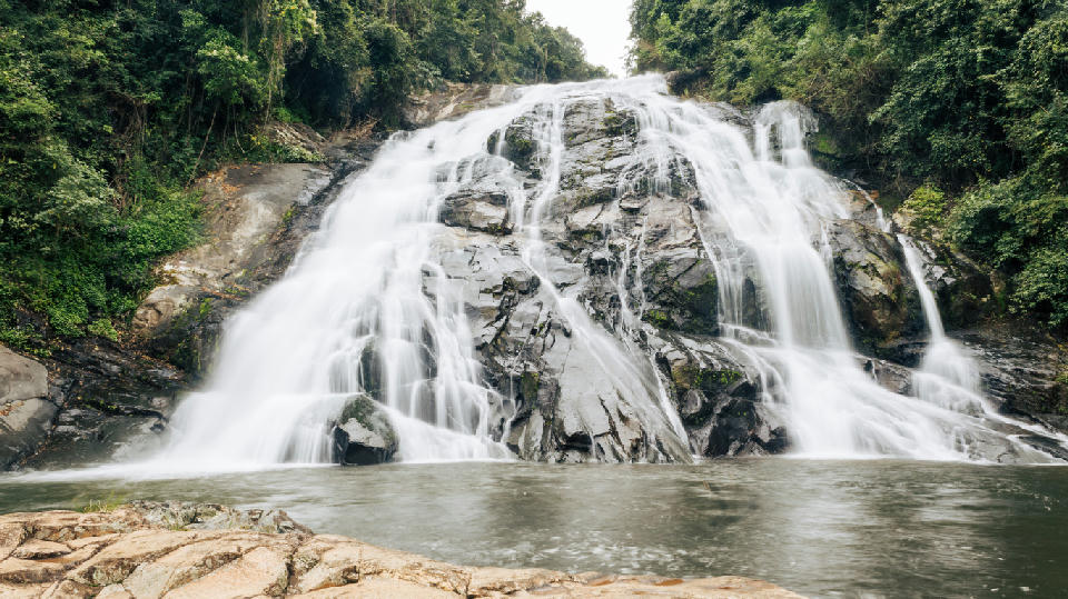 Debengeni Falls cascading over granite rock slabs into a forest-lined pool in Magoebaskloof, Limpopo, South Africa.
