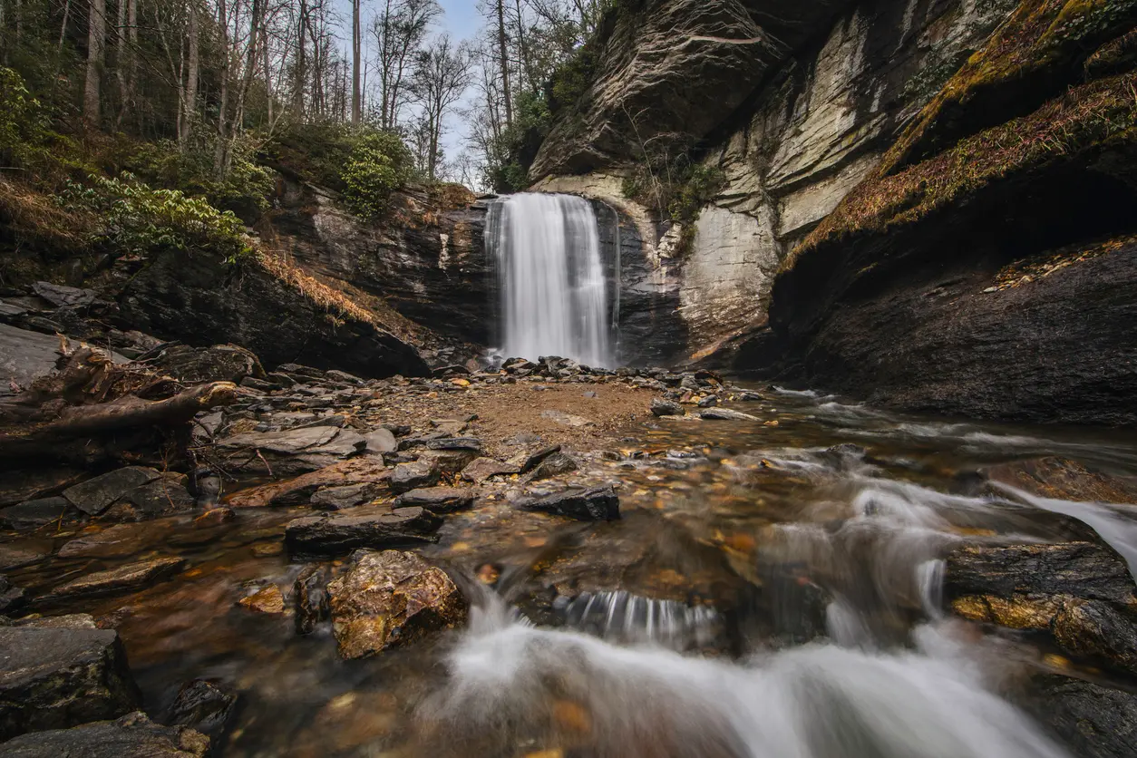Long exposure photograph of Looking Glass Falls surrounded by layered rock walls and forest in Pisgah National Forest, North Carolina.