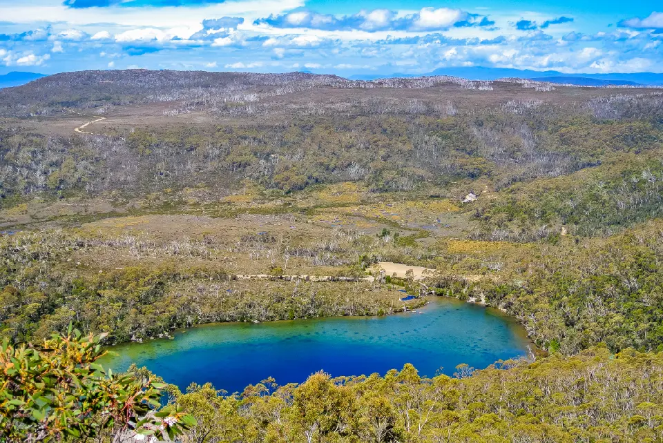 Panoramic view over a glacial lake, eucalypt forest and rugged highlands in Mount Field National Park, Tasmania.