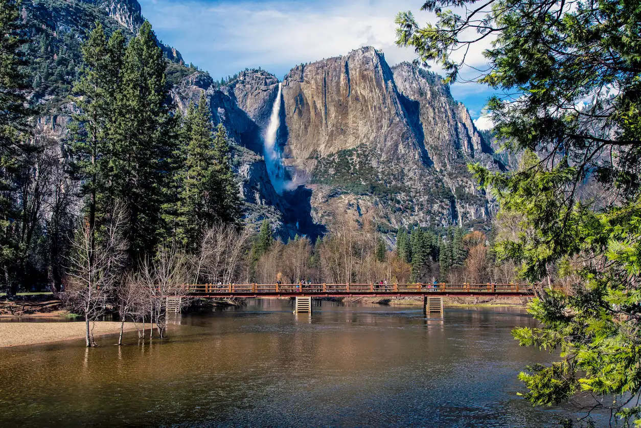 Sentinel Bridge crossing the Merced River with Yosemite Falls centered behind in Yosemite Valley.