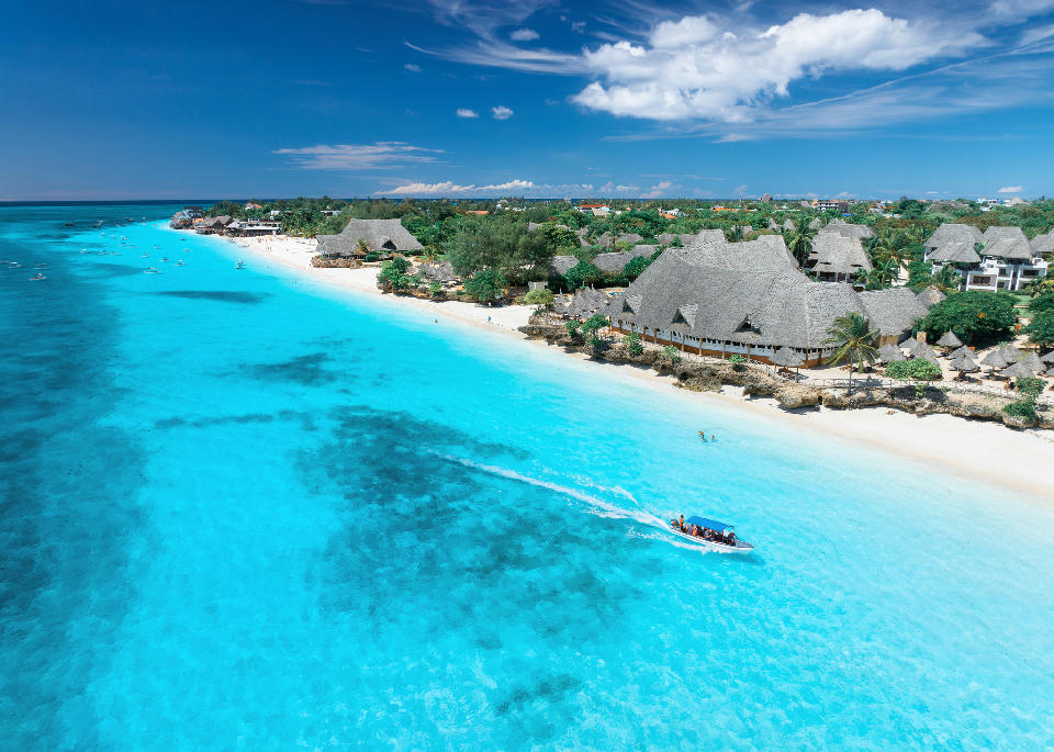 Drone view of Nungwi Beach with white sand, turquoise Indian Ocean, palm-fringed resorts, and tropical coastline, Zanzibar, Tanzania.